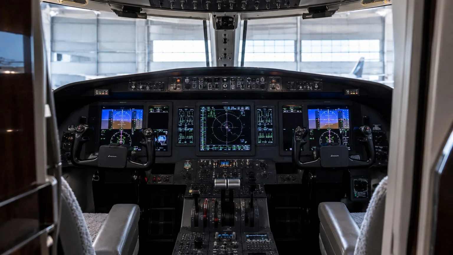 The glass cockpit of a business jet after an interior detail, avionics displays lit and both seats covered