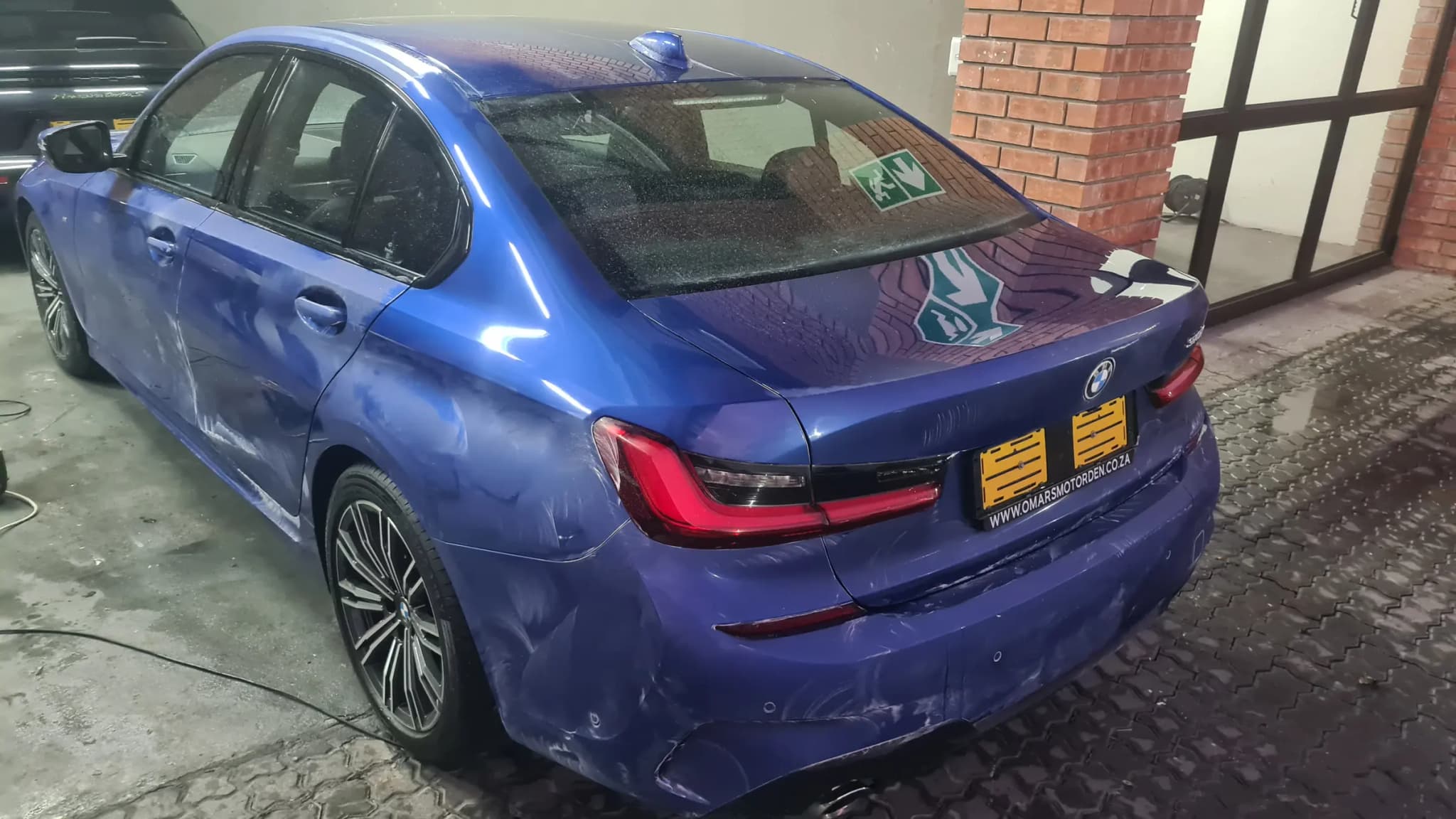 A blue BMW 3 Series photographed outside the wash bay before correction, still wet