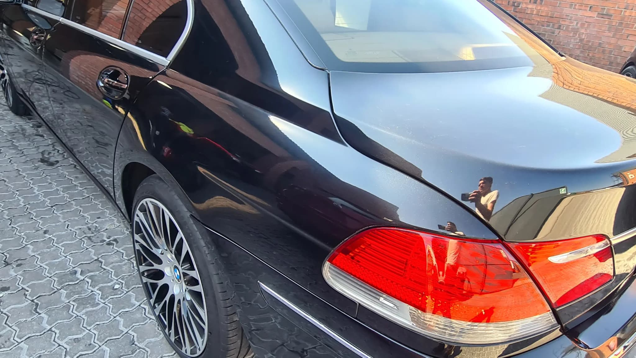 The corrected rear quarter and tail lamp of the same BMW 7 Series, reflection running clean through the curve