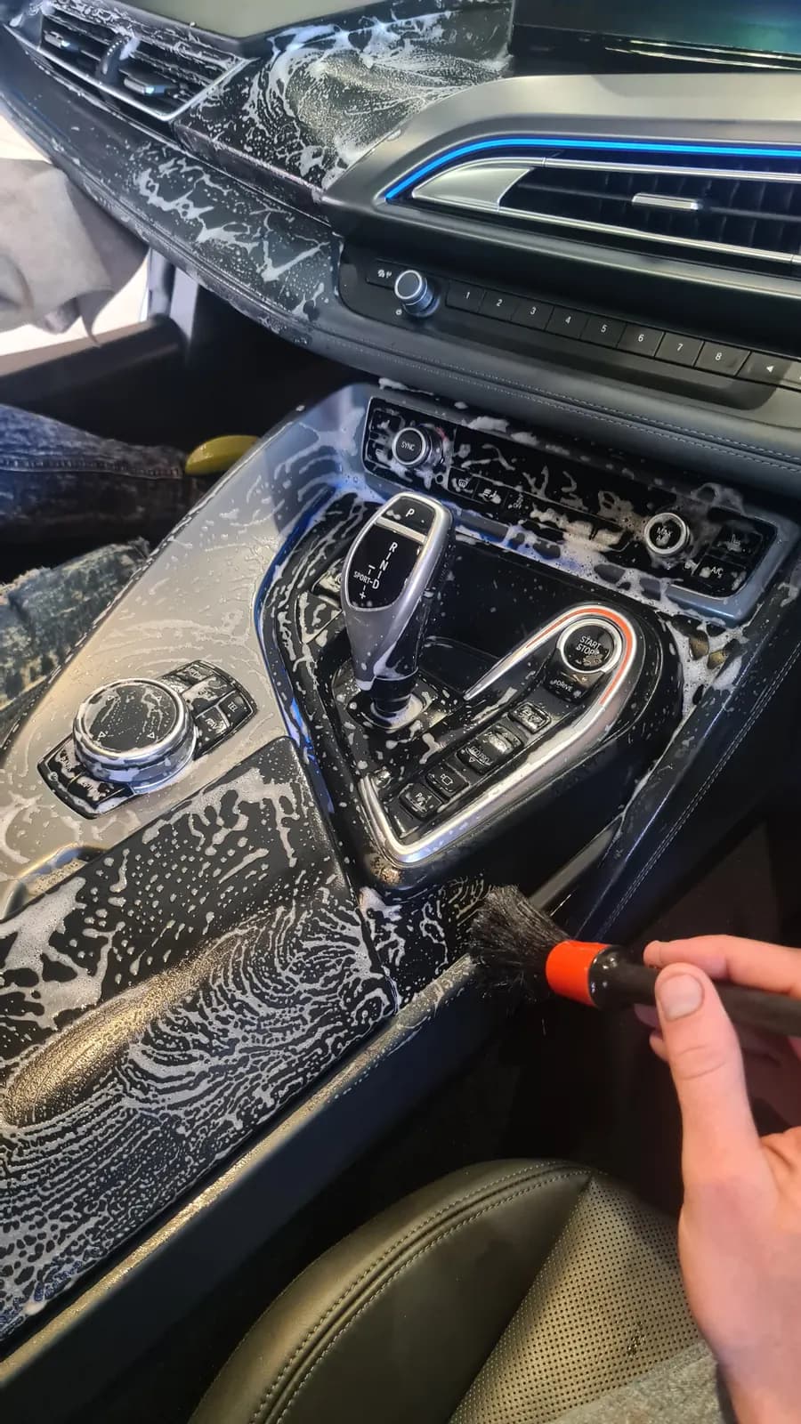 A detailing brush working foam through the switchgear of a car console