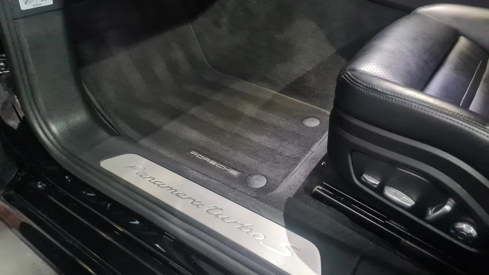 A cleaned Porsche door sill, seat base and floor mat after protection was applied