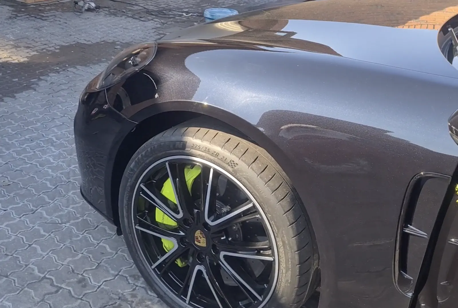 A cleaned and coated Porsche wheel face and arch, the paint above it holding a clean reflection